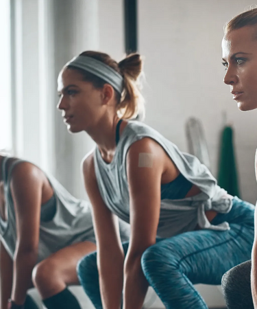 Three women in athletic wear performing a squat exercise in a gym.
